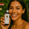 Éminence Organic Skin Care Clear Skin Willow Bark Booster-Serum flesje, op een houten ondergrond met een bloemrijke achtergrond.
