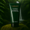 Labrains Skin Perfecting Adu Uzlabojoša Sejas Pilinga Maska potje, 50 ml, op een mossige rots met een waterval en groene jungle-achtergrond.